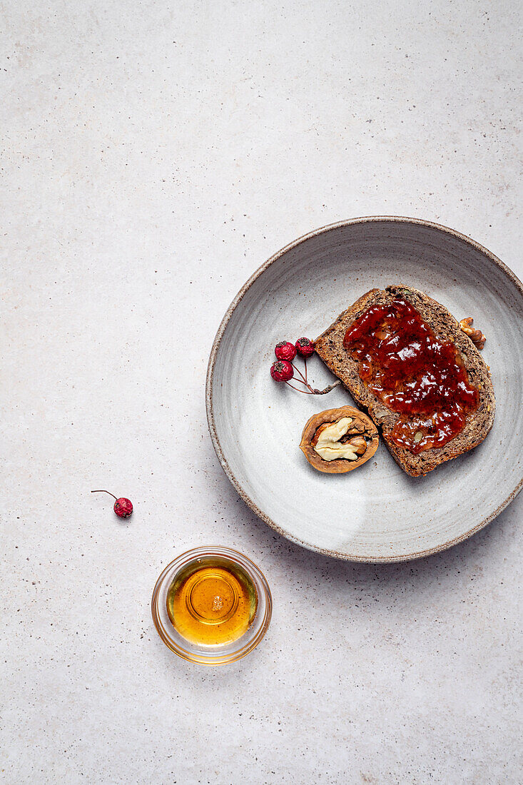 Top view of rye bread with jam near half of walnut composed with honey