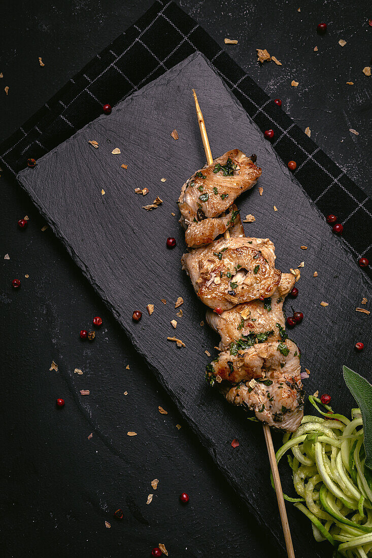 From above of appetizing freshly cooked meat on skewer served on tray on black table
