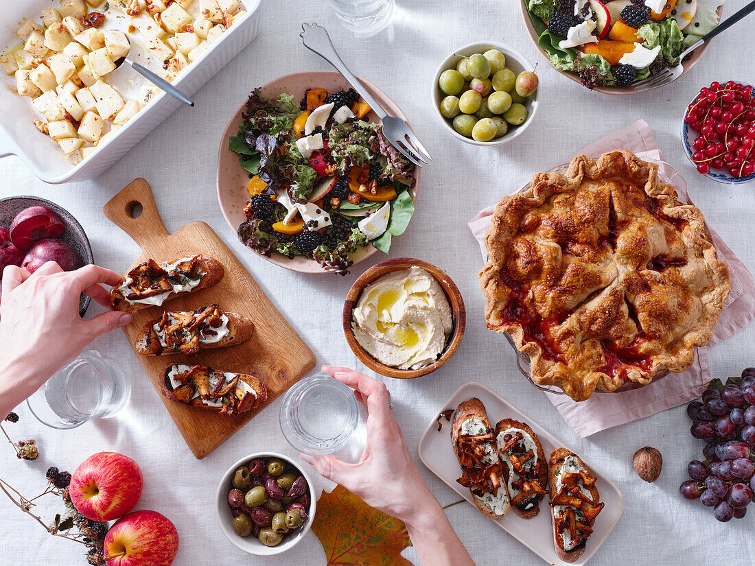 Vegetarisches Abendessen mit verschiedenen Snacks und Gerichten: Salatteller, Bruschetta, gebratenes Gemüse und ein Kuchen