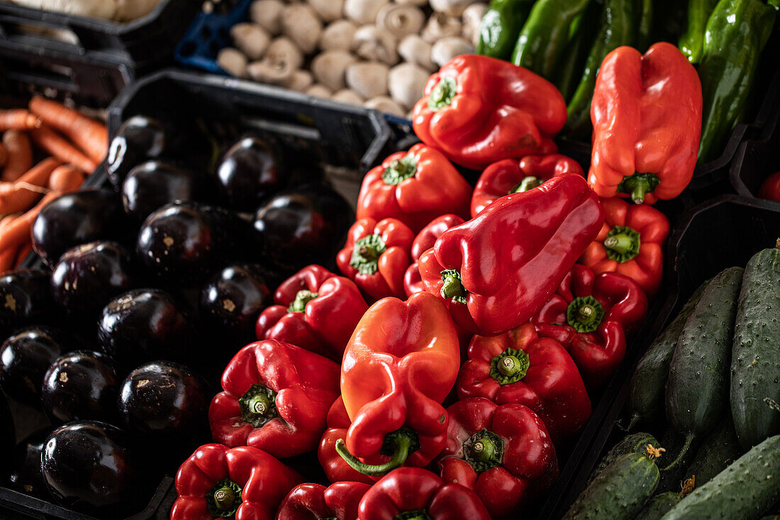 From above of ripe bell peppers cucumbers carrots and mushrooms placed on stall in local market