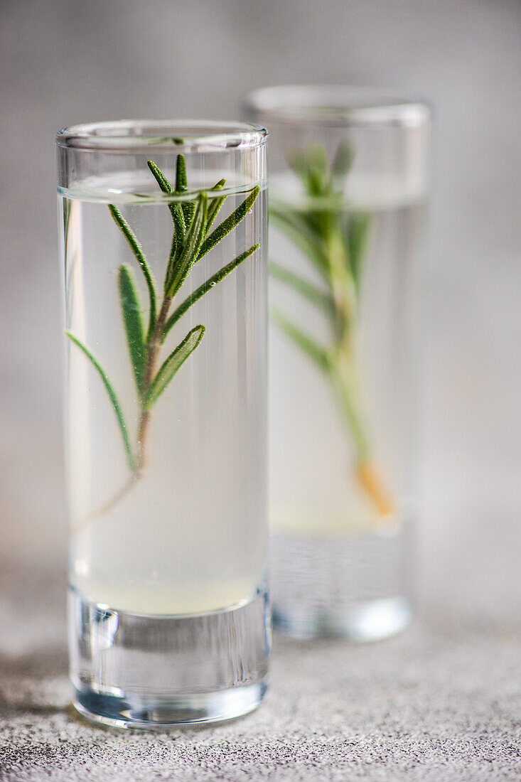 Gläser mit Rosmarin-Wodka werden auf einem Betontisch serviert