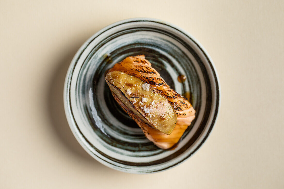 Draufsicht auf leckere japanische Nigiri-Sushi mit geräuchertem Lachs und flambierter Gänsestopfleber, serviert auf einem Teller im Restaurant