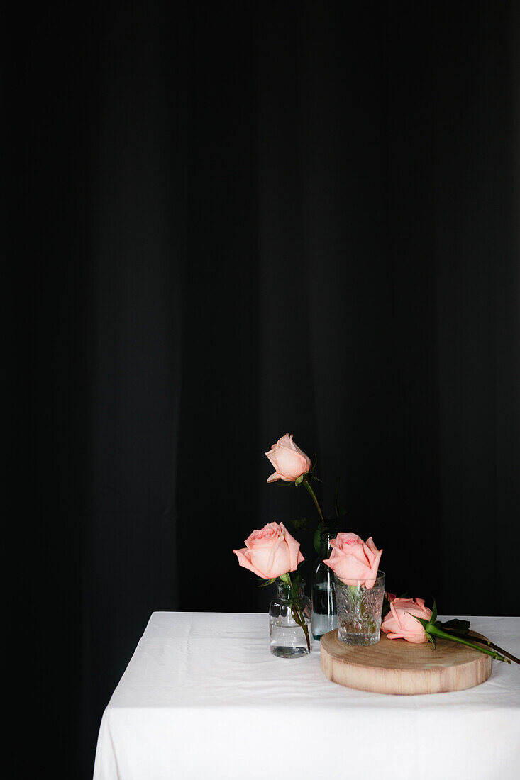 Pink roses inside glass vases placed on table against black background