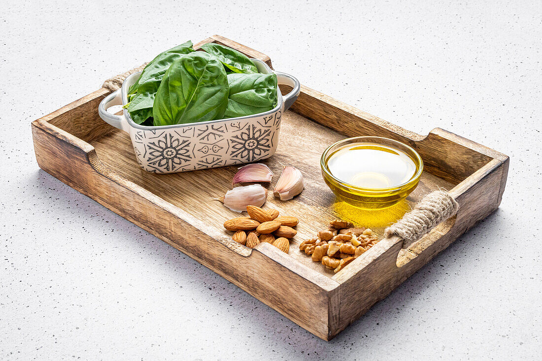 Öl-Knoblauch-Nüsse und frischer Spinat auf einem Holzbrett vor der Zubereitung von Pesto-Sauce für Gnocchi