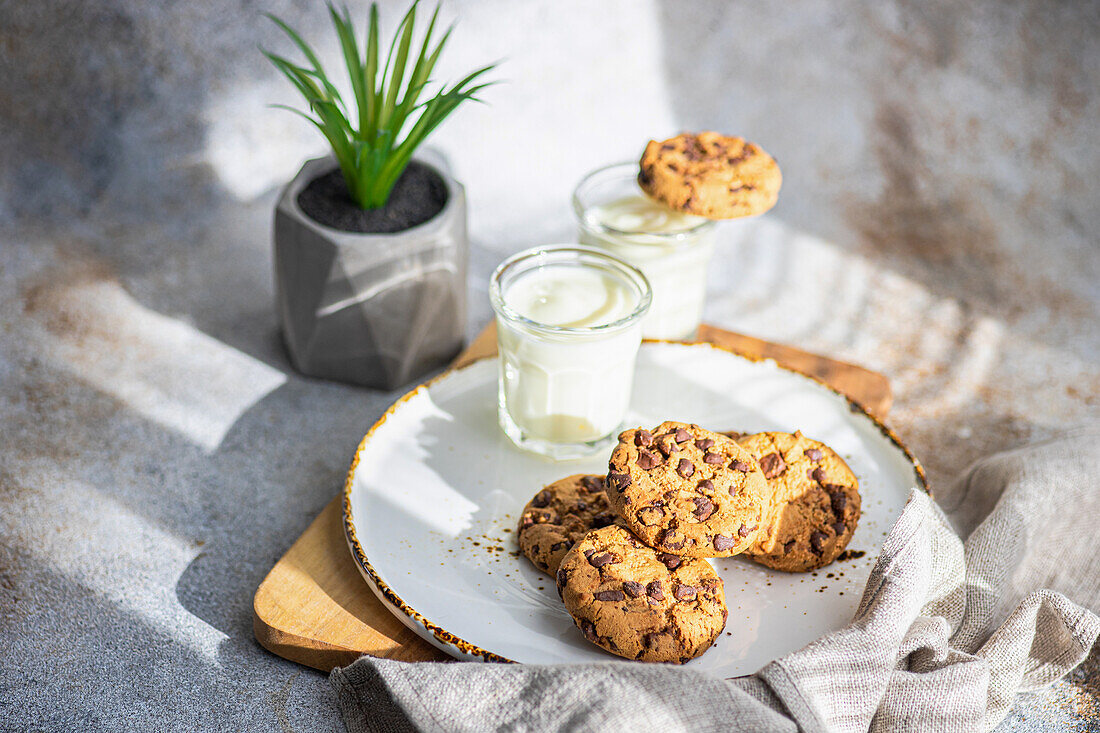 Healthy oat cookies with chocolate and glass of yogurt on the concrete or stone table