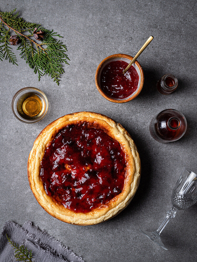 From above of yummy homemade sweet cheesecake placed against jar with sauces and bowl of jam on gray table