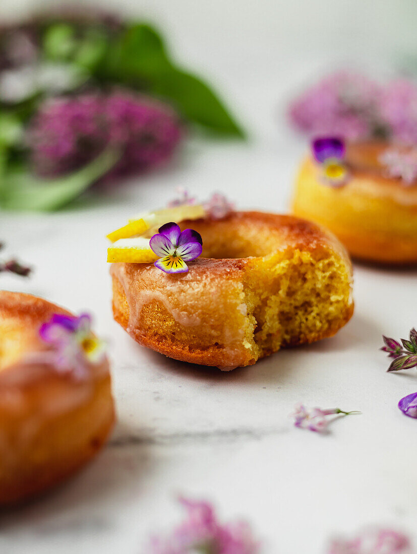 From above of yummy doughnuts with fresh lemon slices and Lavandula flowers on marble surface
