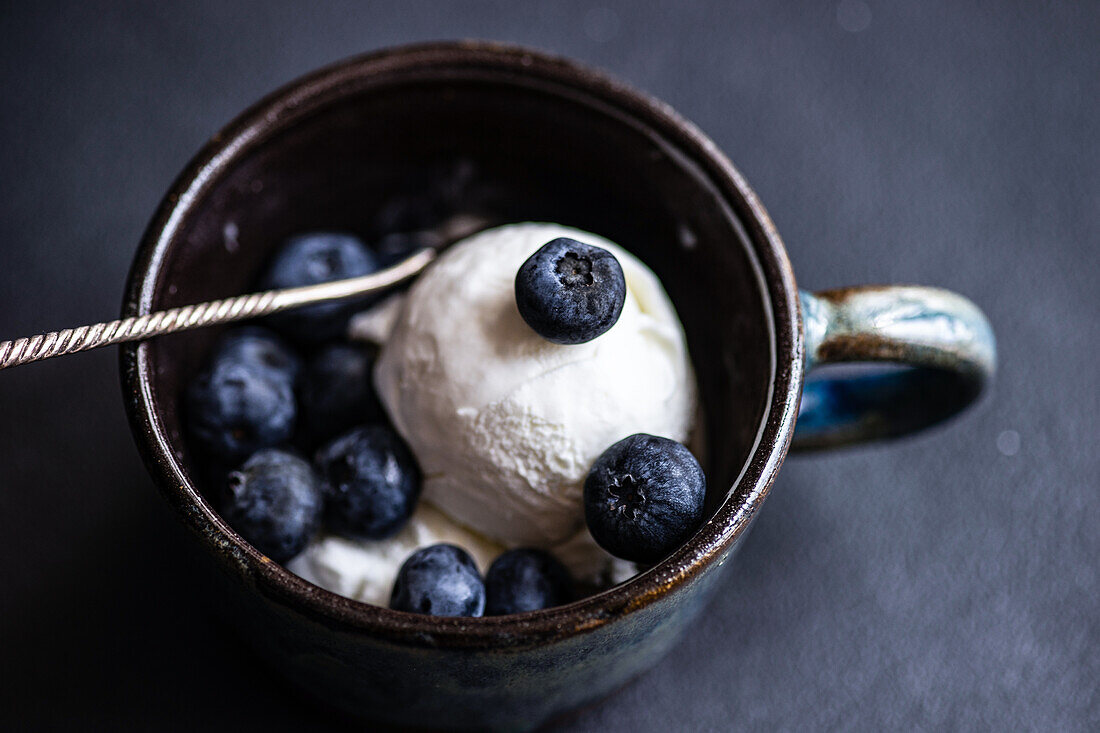 From above bowl full of delicious ripe blueberries placed on black background