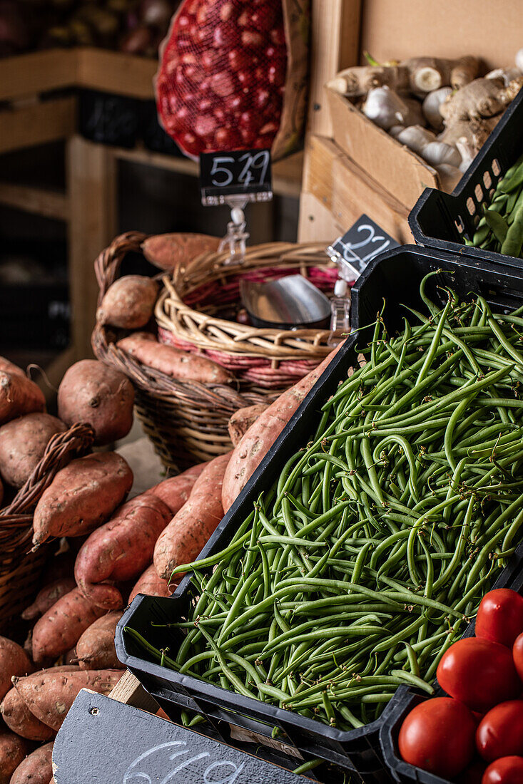 From above of green beans sweet potatoes and tomatoes placed on stall in local market