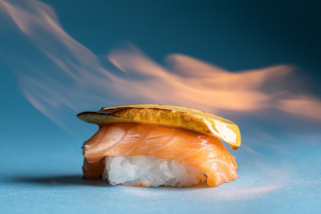 Leckeres traditionelles japanisches norwegisches Nigiri mit frischem Lachs und köstlicher flambierter Gänsestopfleber vor blauem Hintergrund in einem hellen Studio
