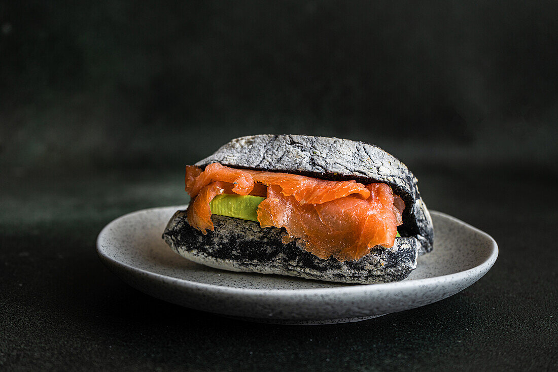 Healthy snack with sour dough and activated carbon bun and salmon fish in sandwich