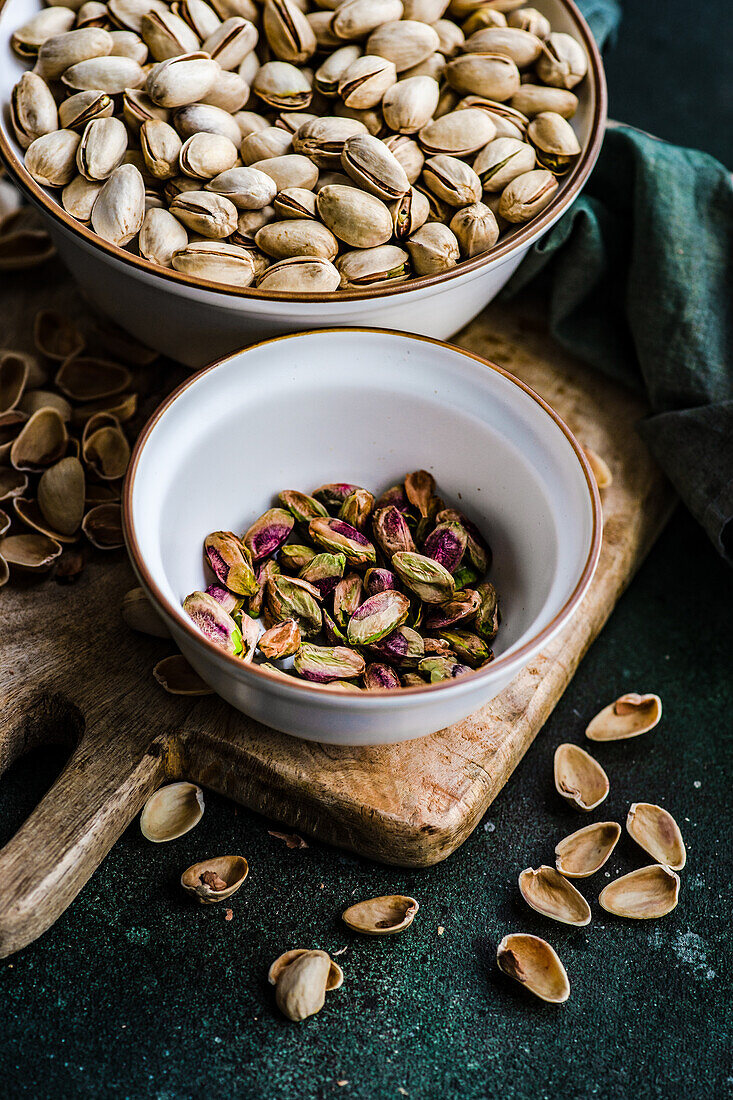 From above organic and raw pistachio nuts in the bowls on green table background