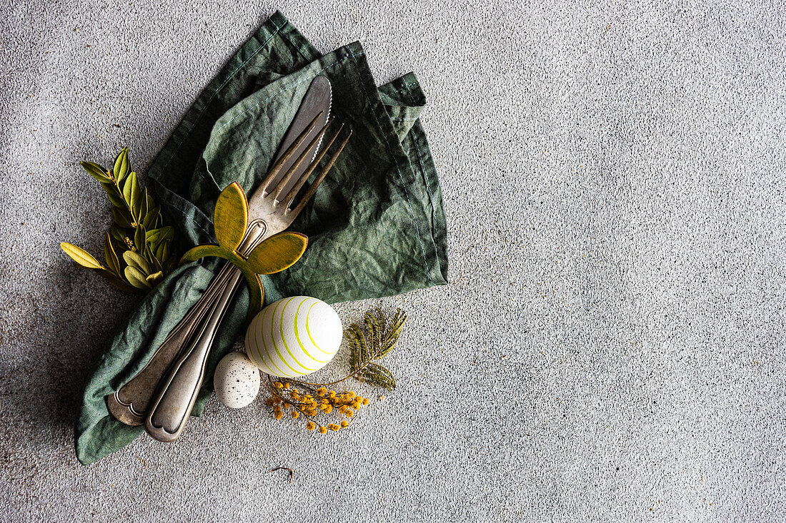 From above place setting for Easter dinner in green color on concrete background