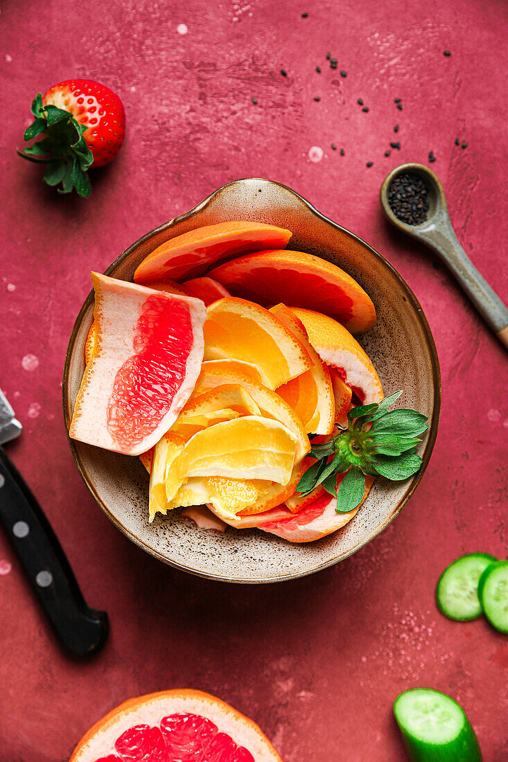 Draufsicht auf einen appetitlichen Orangensalat mit Basilikum in einer Schüssel, die neben Zutaten und einem Löffel mit Chiasamen steht