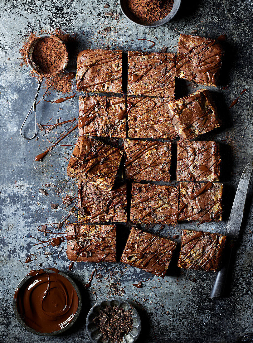 Draufsicht auf leckere Schokoladen-Brownies mit Topping und Kakaopulver auf grauer Fläche