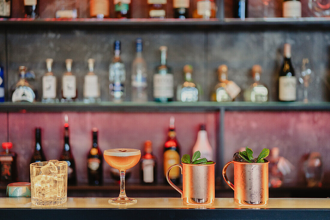 Moscow mule and sour cocktails served with glass with ice cubes on counter in bar