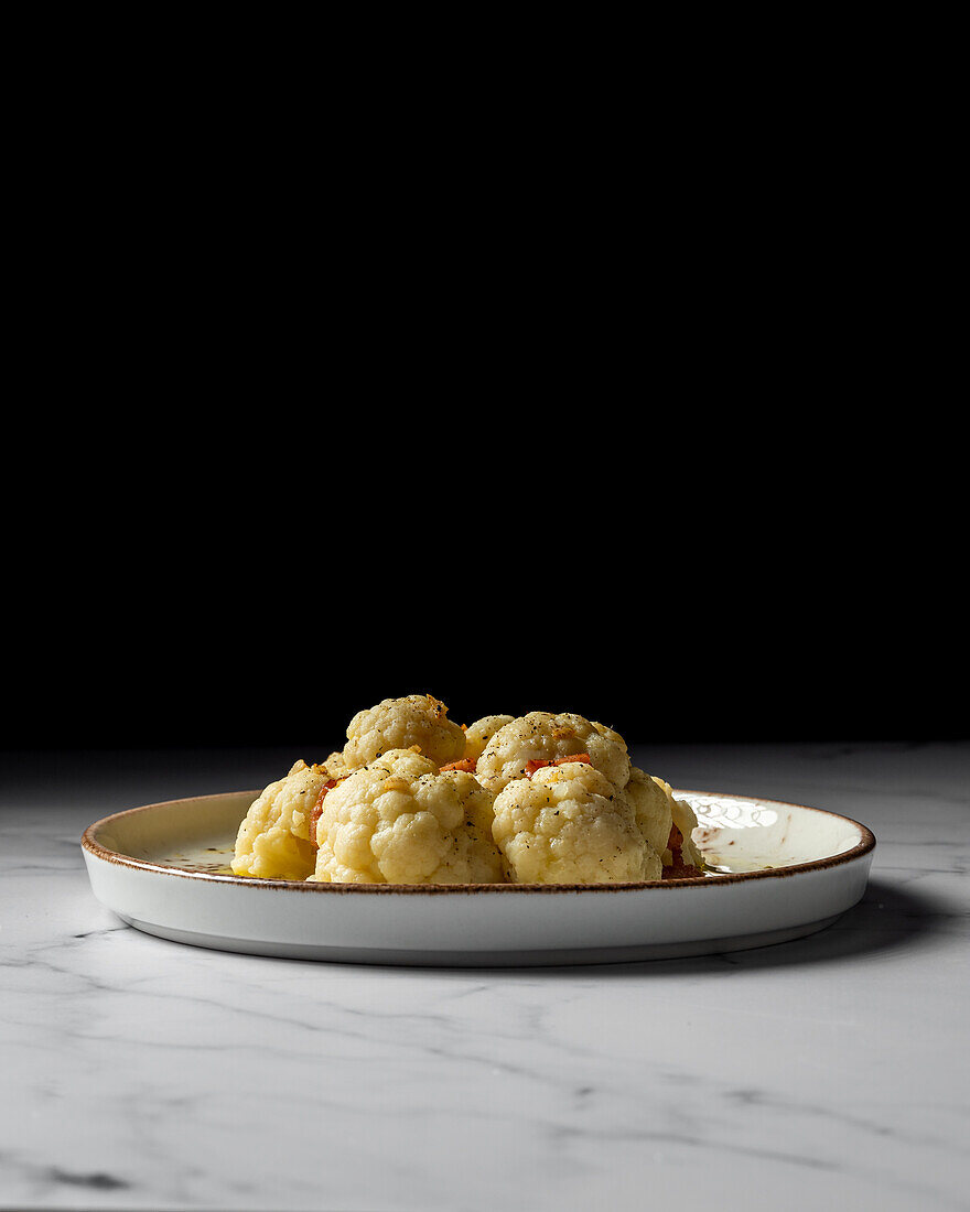 Appetizing cauliflower with bacon drizzled with oil and sprinkled with spices