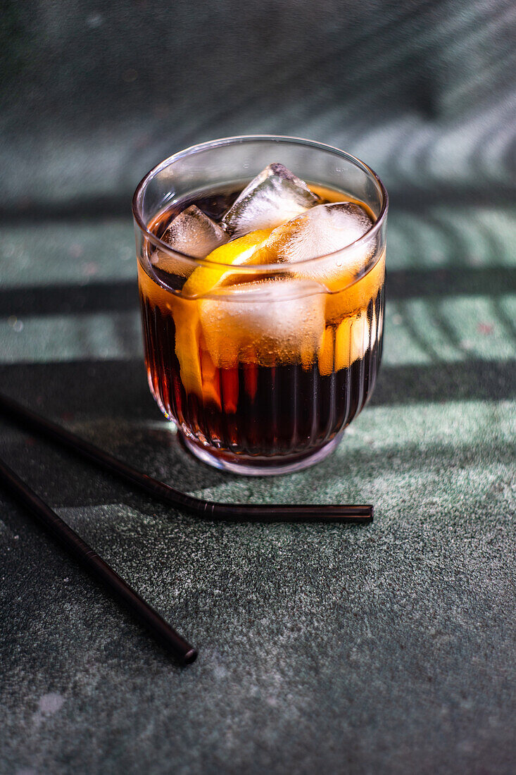 Alkoholcocktail Cuba Libre mit Orangenscheibe und Eis im Glas