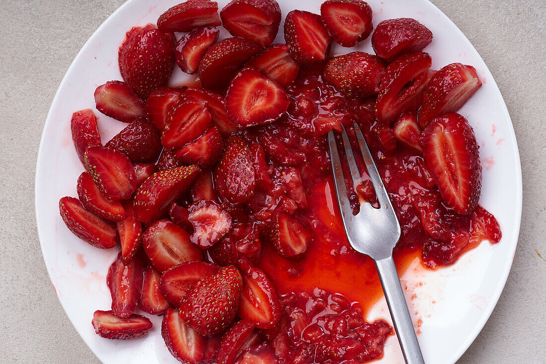 In Scheiben geschnittene Erdbeeren mit Zucker überzogen auf einem Teller. Kochen von Dessert oder Marmelade