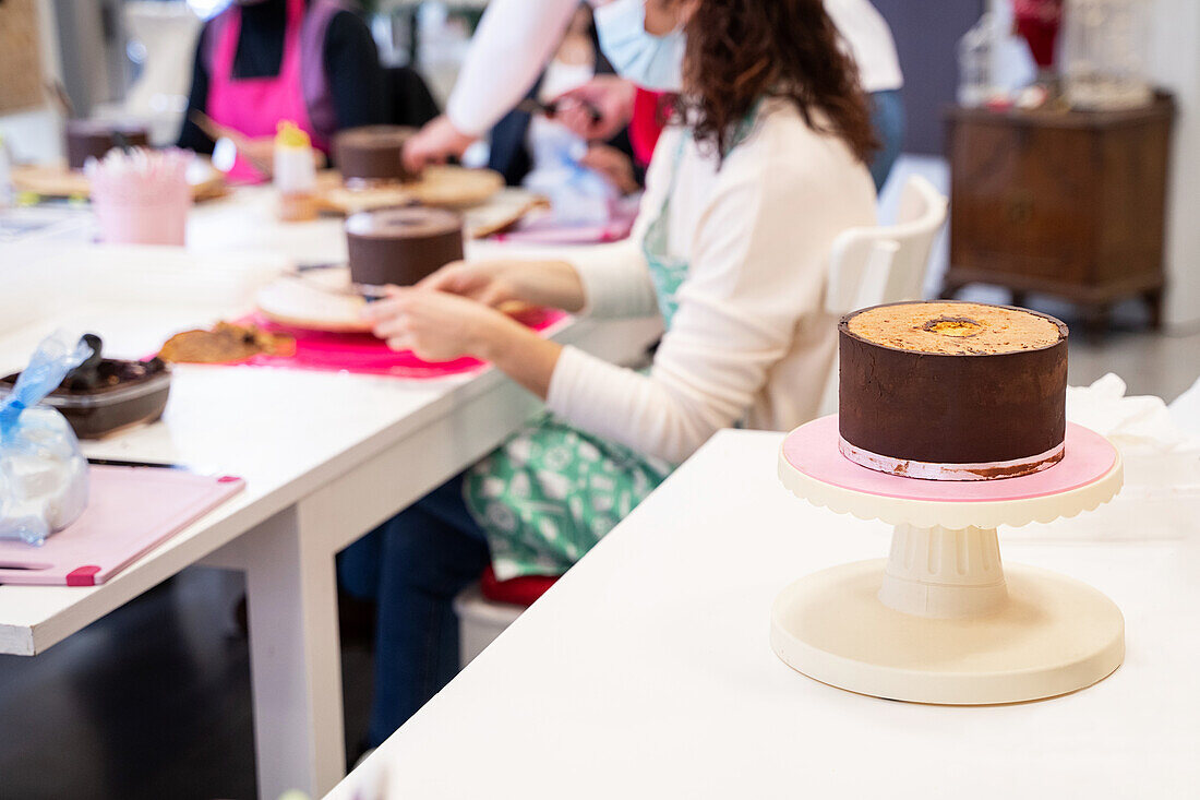 Köstlicher Schokoladenkuchen auf einem festlichen Ständer vor einem Chefkoch, der in einer Bäckerei Desserts zubereitet