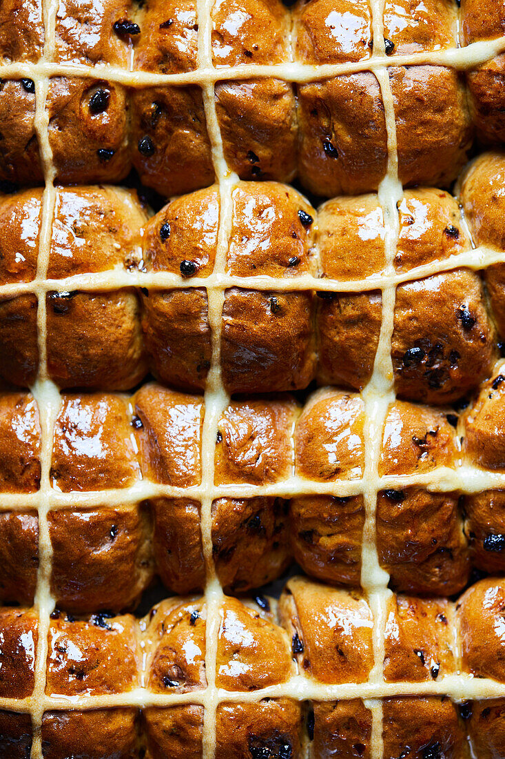 Ansicht von oben Vollbild Hintergrund der köstlichen gebackenen hausgemachten Hot Cross Brötchen mit Sahne und Rosinen