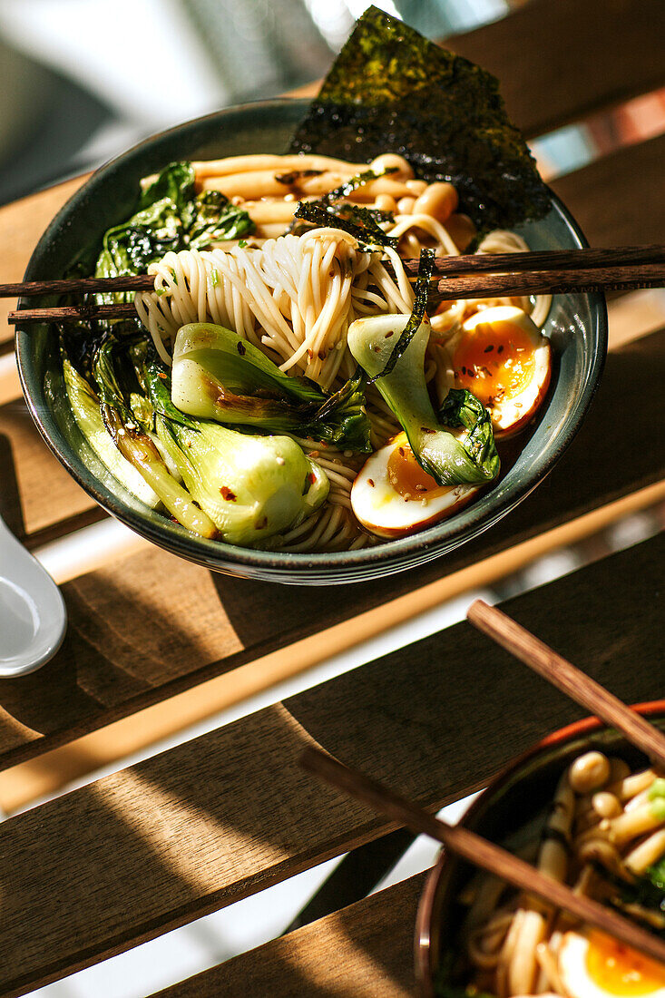 From above bowl with tasty ramen for lunch placed on wooden table in cafeteria