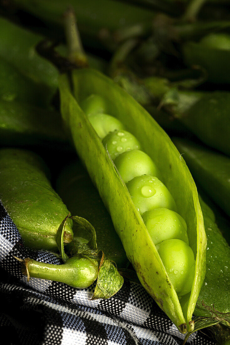 From above pile of ripe whole and opened pods with peas placed together in basket