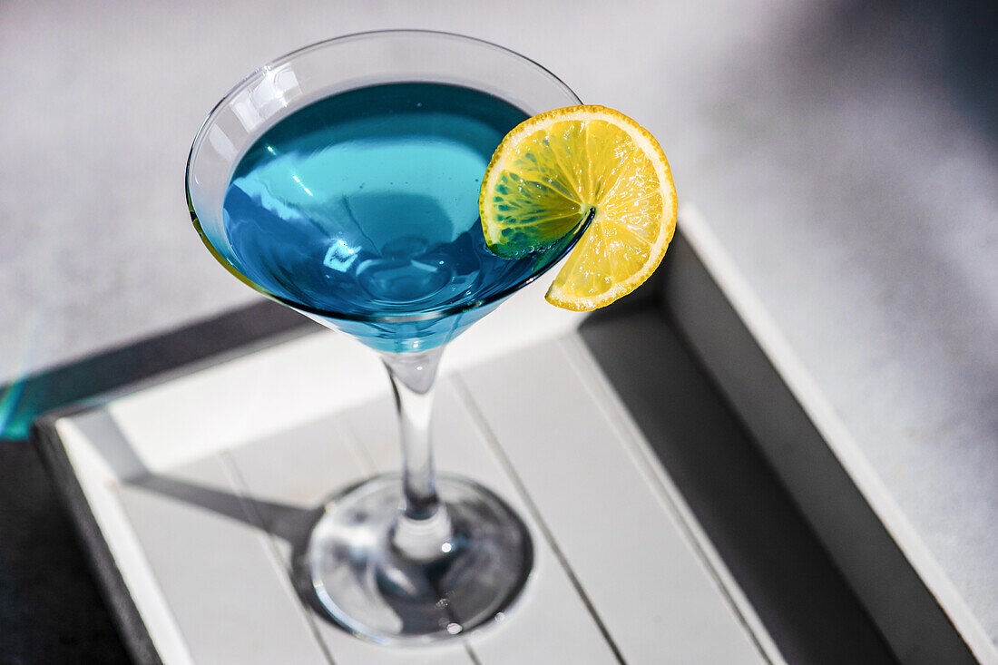 Glass of blue kamikaze drink on stone table in modern style