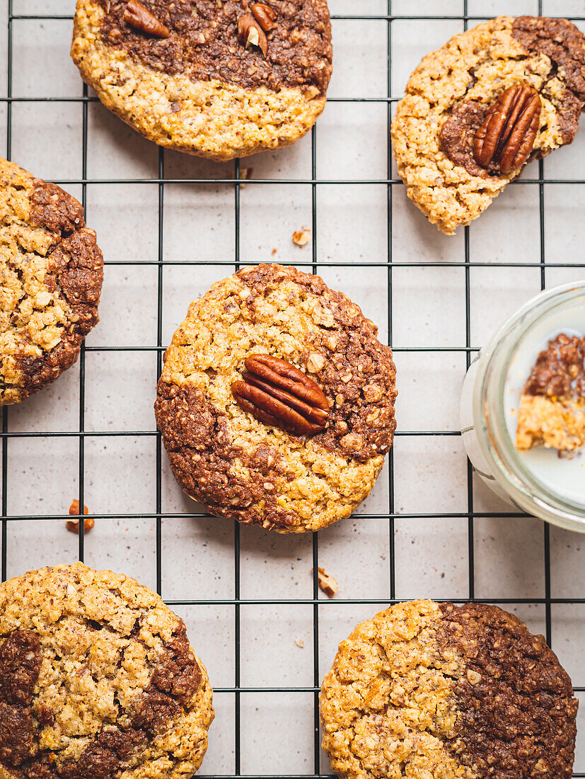 Top view of appetizing walnut cookies in glass on milk and on baking net served on table