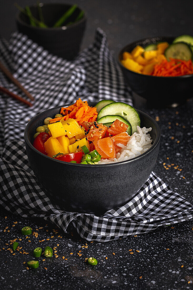 High angle of Asian poke with salmon and rice with assorted vegetables served in bowl on table with chopsticks in restaurant