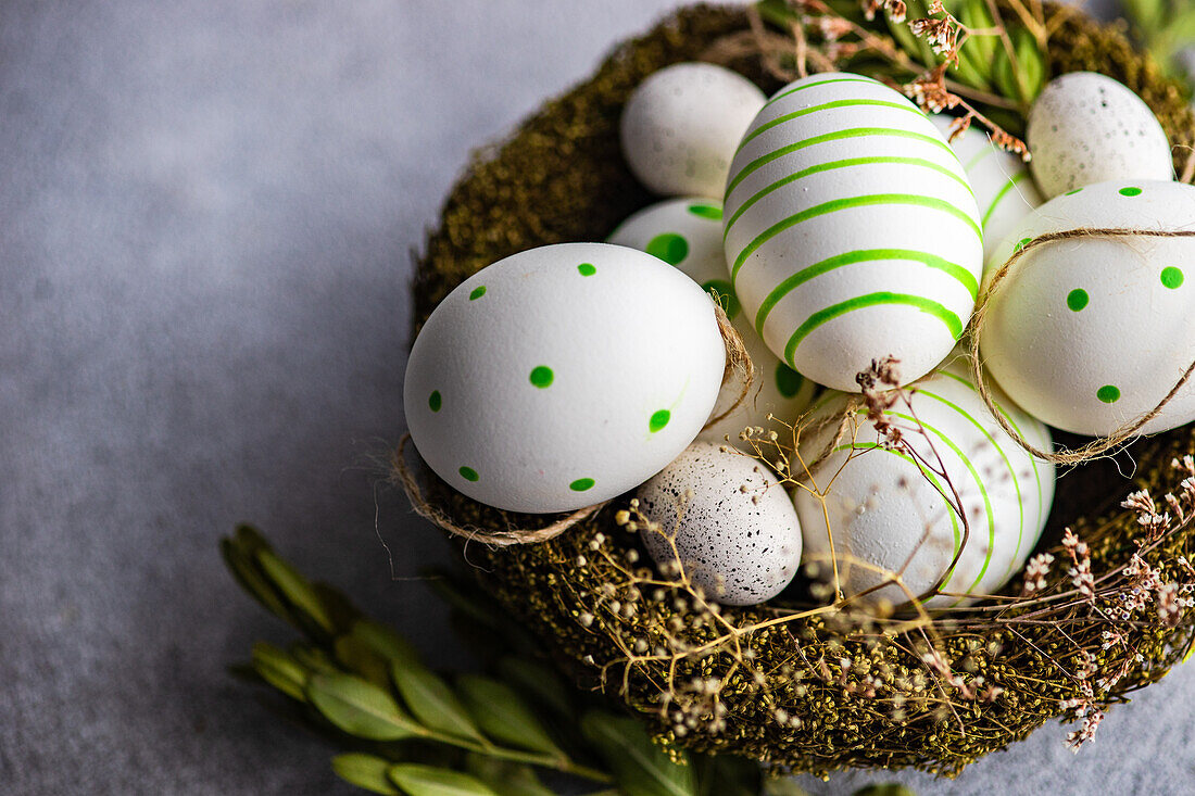From above nest full of colored eggs as a easter holiday concept on concrete background