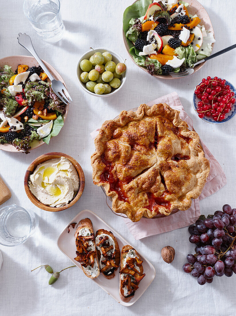 Vegetarian dinner with various snacks and dishes: salad plates, bruschetta, roasted vegetables and a pie