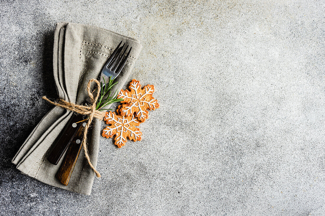 Von oben Tischtuch Serviette mit Besteck in der Nähe von Lebkuchen Kekse Einstellung für Weihnachten Abendessen auf Beton Tisch auf weißem Hintergrund