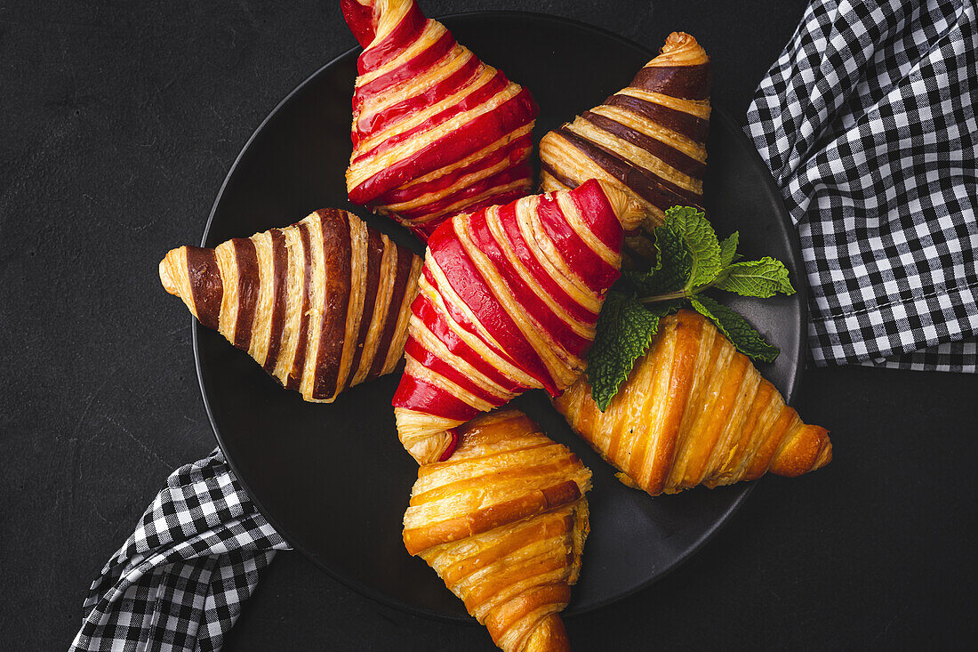 Blick von oben auf verschiedene süße Croissants, die in einem Korb auf dem Frühstückstisch serviert werden