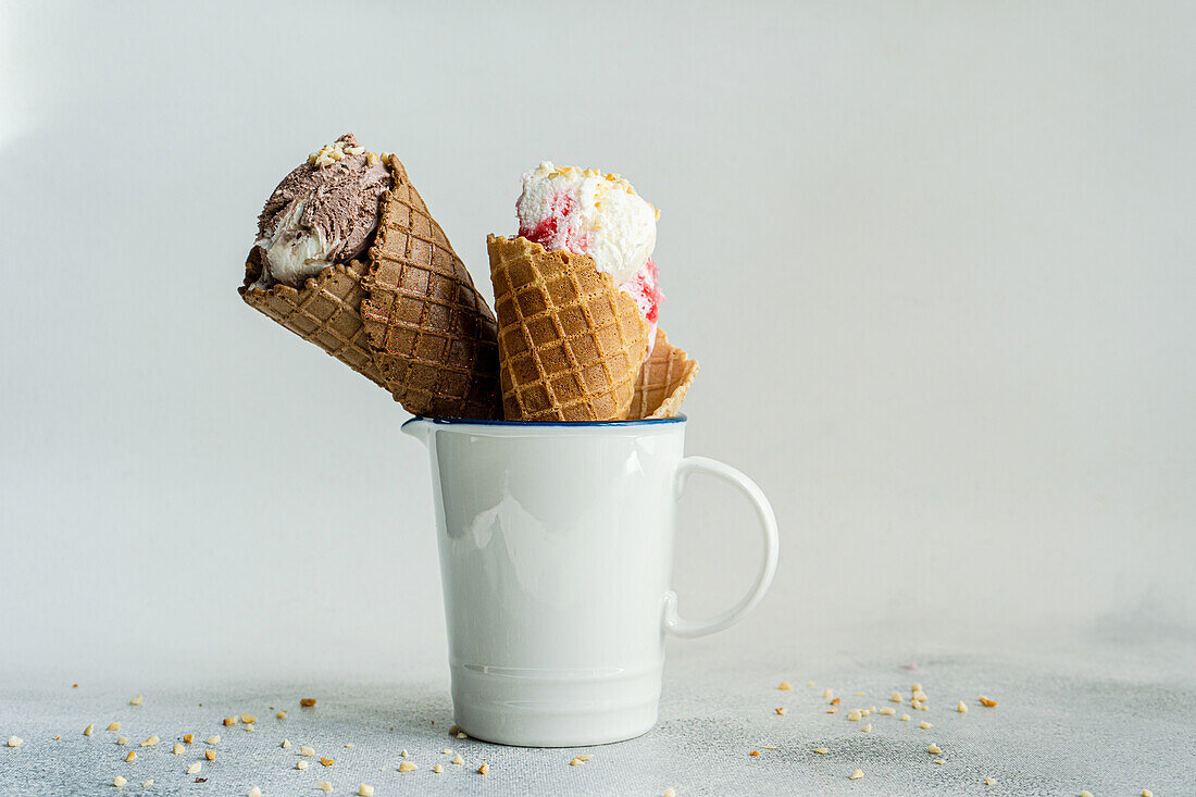 White cup with waffle cones filled with ice cream on concrete table