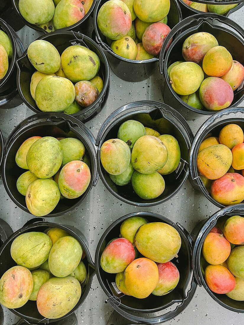 Top view of fresh juicy mangoes in black buckets placed on table in local market of Australia