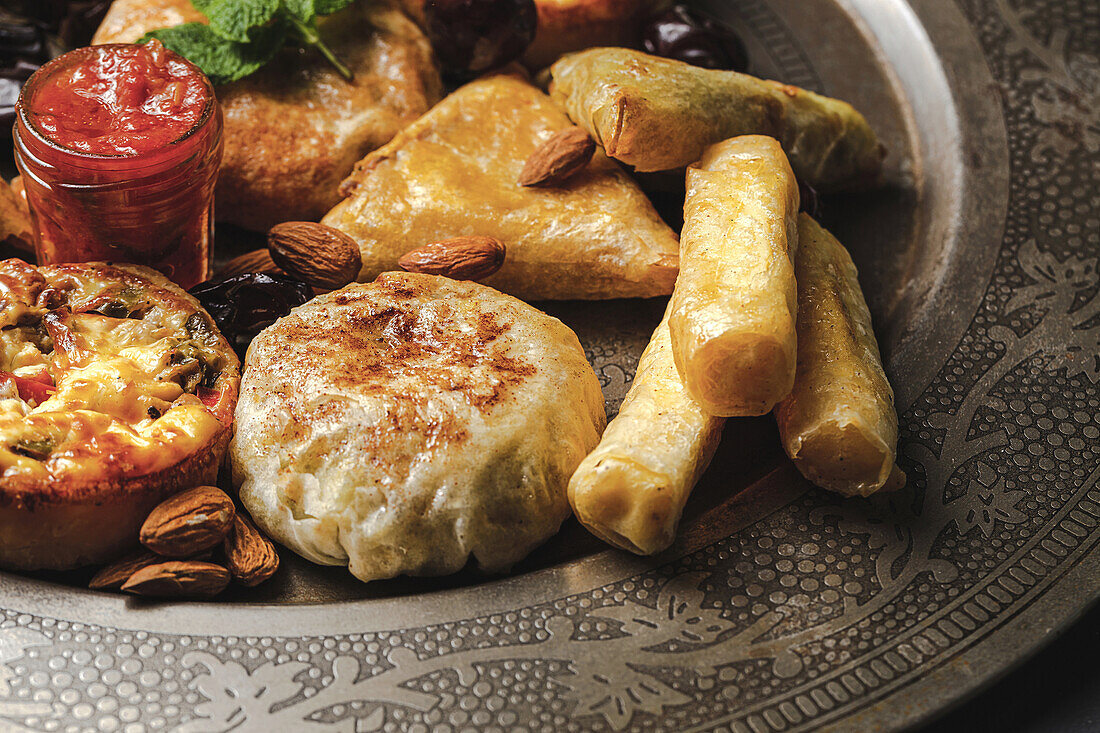 High angle of assorted tasty Arabic food with salsa and fresh mint leaves near almonds during Ramadan holidays