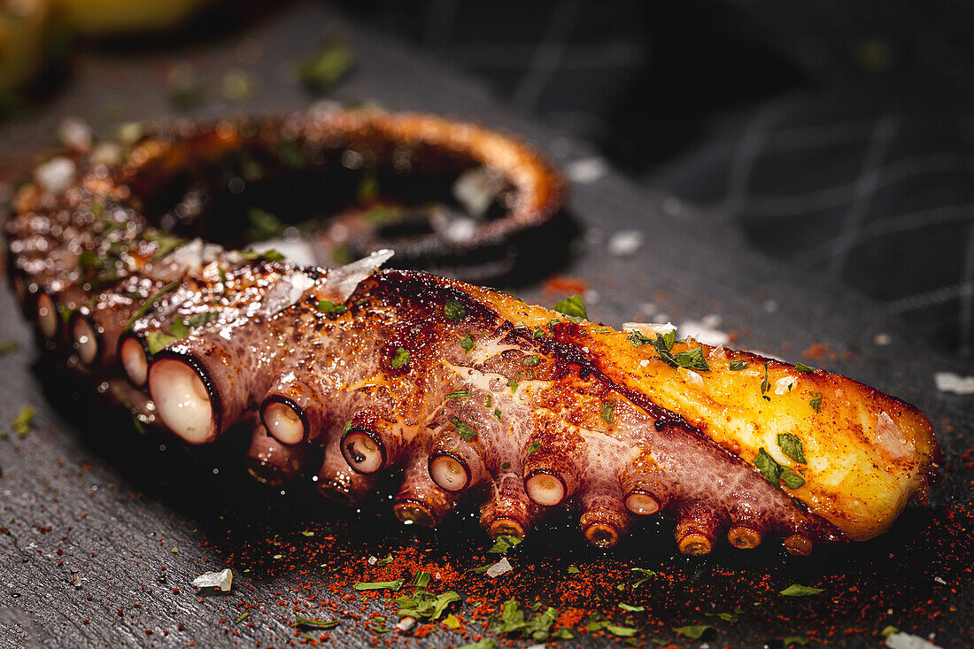 Delicious grilled octopus tentacle served with spices on wooden board