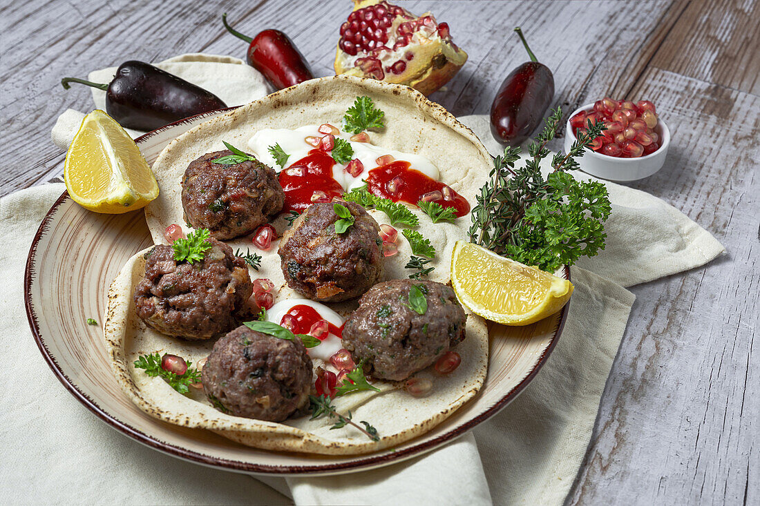 Traditionelle hausgemachte Rind- und Lammfleischbällchen mit arabischem Brot, Tomatensauce, Granatapfel und Kräutern. Halal-Essen