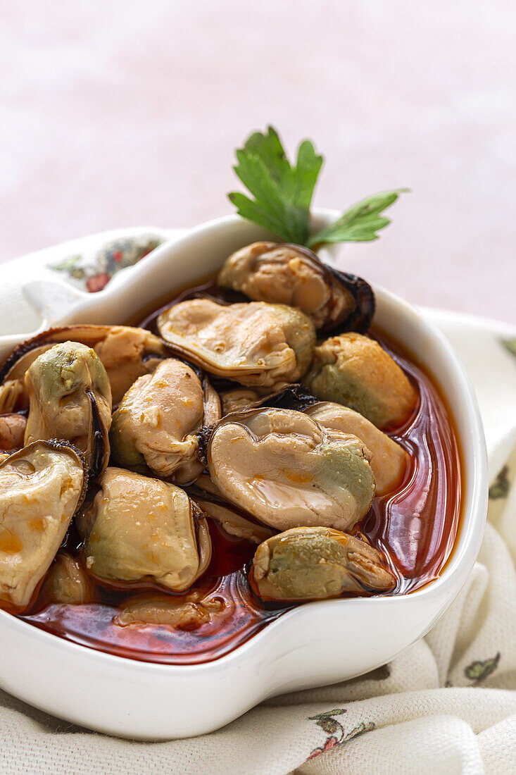 From above ceramic plate with yummy mussels in sauce standing on piece of cloth on gray background