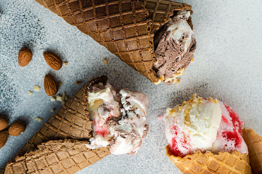 From above waffle cones with cherry and chocolate ice cream on concrete background
