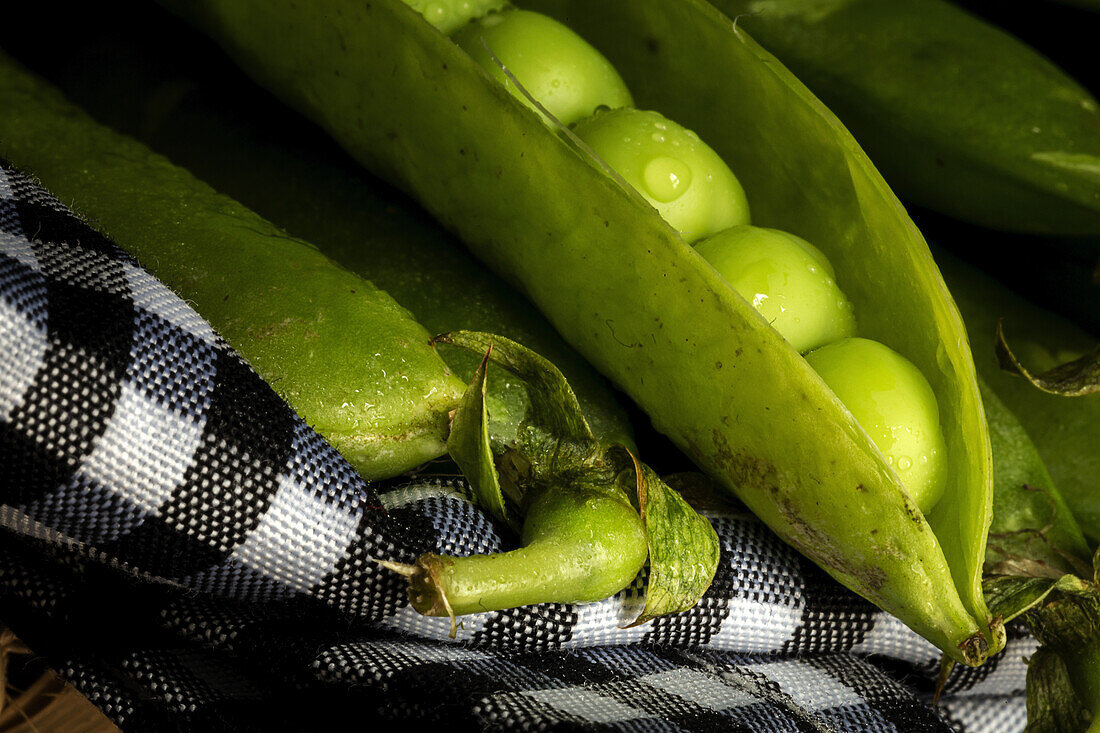 From above pile of ripe whole and opened pods with peas placed together in basket