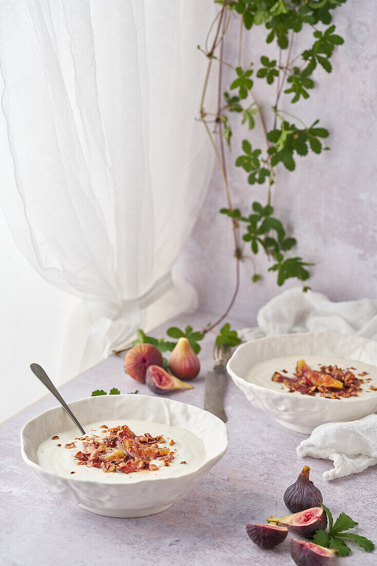 Ceramic bowls with delicious porridge and sweet fig slices on top for breakfast against creeping plant