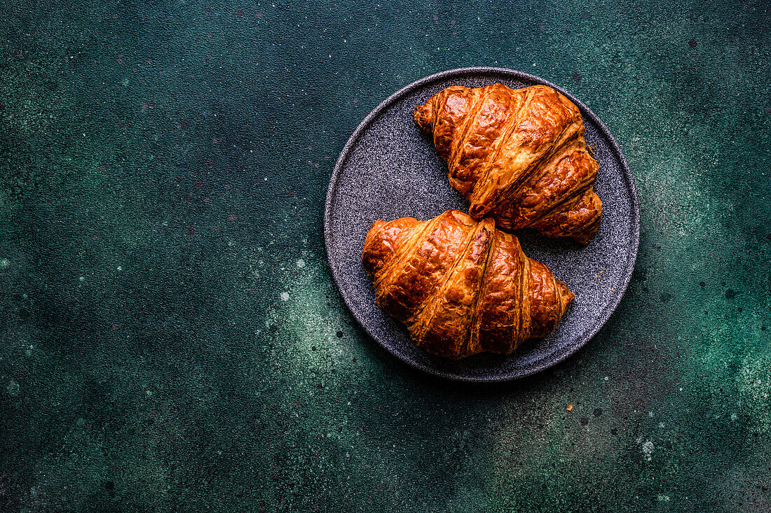 From above fresh baked croissant with jam on the concrete blue table