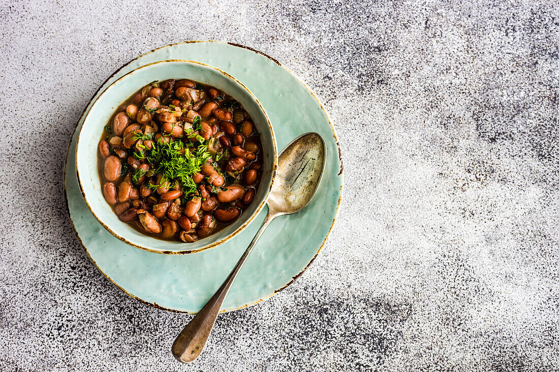 Vegetarische Bohnensuppe, serviert in einer Keramikschale mit Zwiebel und Korianderkraut