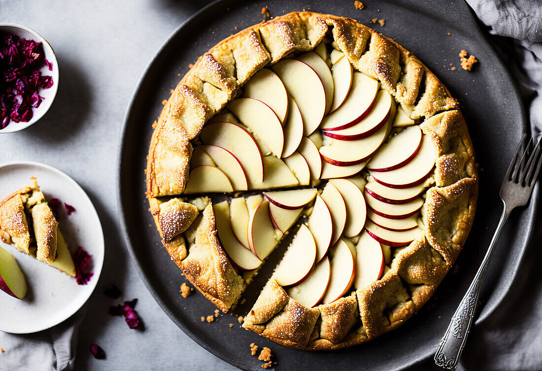 Top view of delicious homemade galette cake decorated with apple slices placed on plate with fork