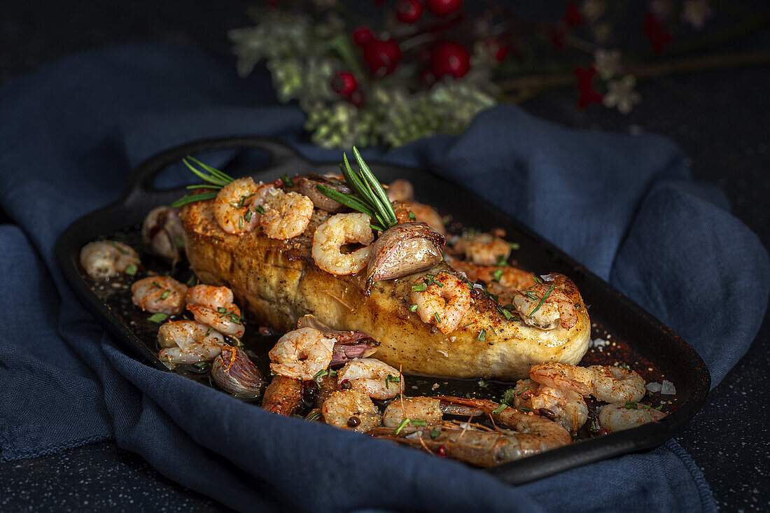 From above of black tray with appetizing baked swordfish served with prawns and confit garlic