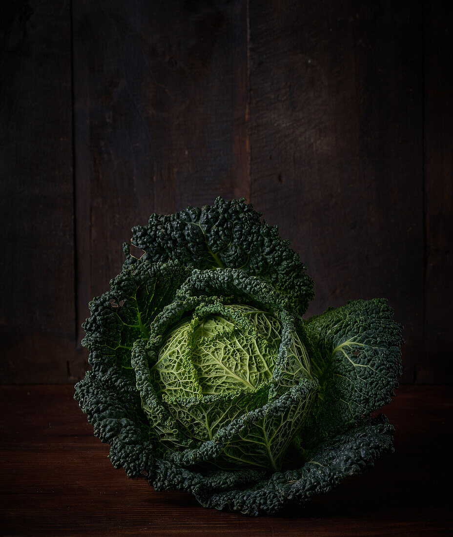 Fresh healthy textured Savoy cabbage with green leaves placed on wooden table in kitchen