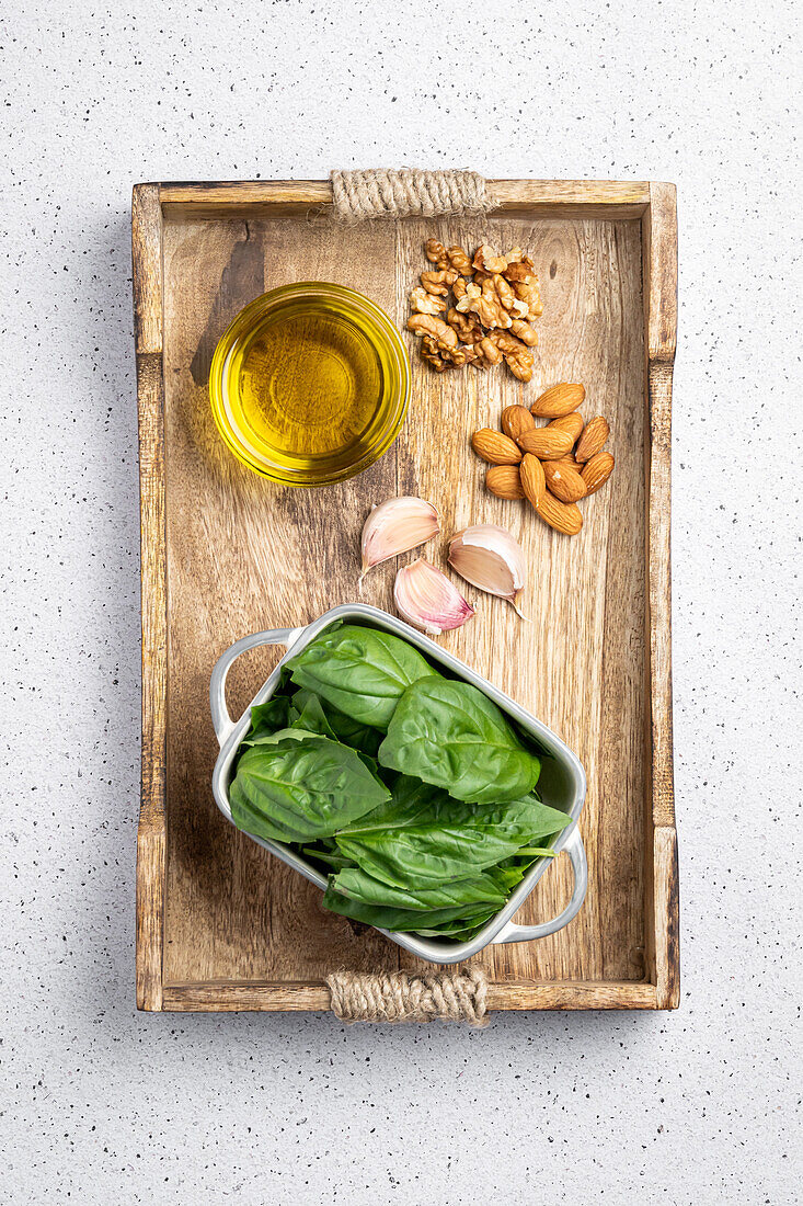 Top view of oil garlic nuts and fresh spinach placed on wooden board before making pesto sauce for gnocchi