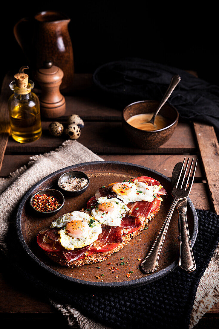 Appetitliches Toastbrot mit Prosciutto und gebratenen Wachteleiern, serviert zum Frühstück auf einem rustikalen Holztisch